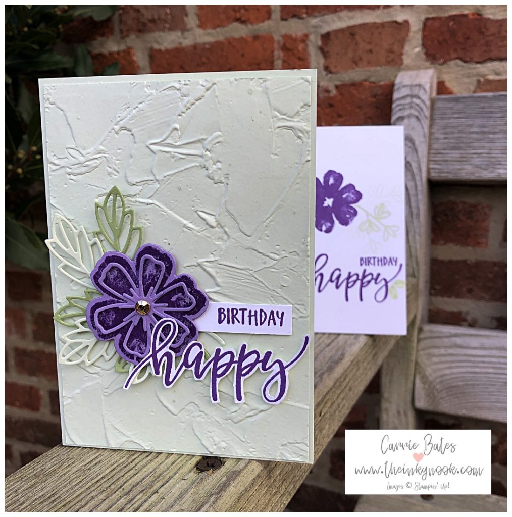 The main card in this image is a very soft green colour with an embossed painted texture to it.  On top of this is a purple multi level style pansy backed with die cut leaf images.  To the right side of the flower are the words Happy Birthday stamped in purple onto a white background.