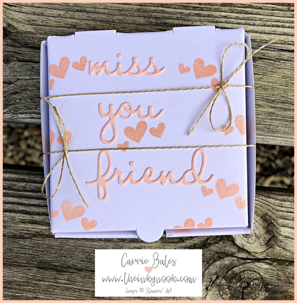 Small white gift box stamped with pink hearts and die cut words "miss you friend" in pink glued on top.  Finished off with two gold twine bows either side of the box lid. Gift box to send love and hugs to a friend
