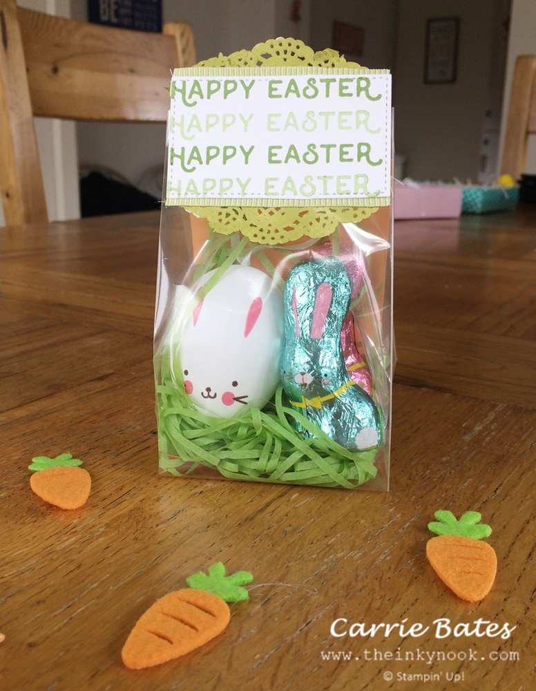 Cellophane bag stuffed with an bunny Easter egg and chocolate rabbit wrapped in foil.  A gift tag tops the cellophane bag and is stamped with Happy Easter in green backed with a green doilie.