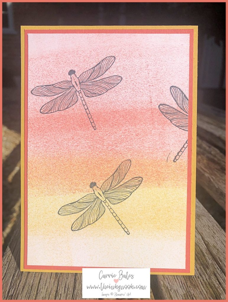 Sponge brayering for cardmaking technique shown by a yellow card topped with a layer showing brayered lines of orange and yellow.  Two black dragonfly outlines are stamped onto the layer and framed by a coral layer.