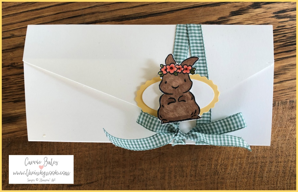 Top profile of a white handmade Easter gift box with a yellow centre wrapped in mint gingham ribbon topped with a Easter bunny wearing a floral crown