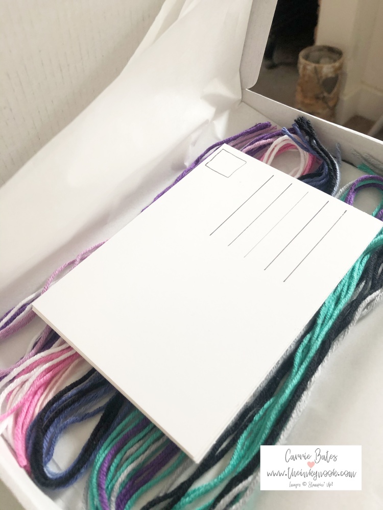 Inside view of the Crafty Pants summer holidays 2021 wellbeing craft kit for children.  Pictured are multiple wool strands to make friendship bracelets and postcards to send to friends/family