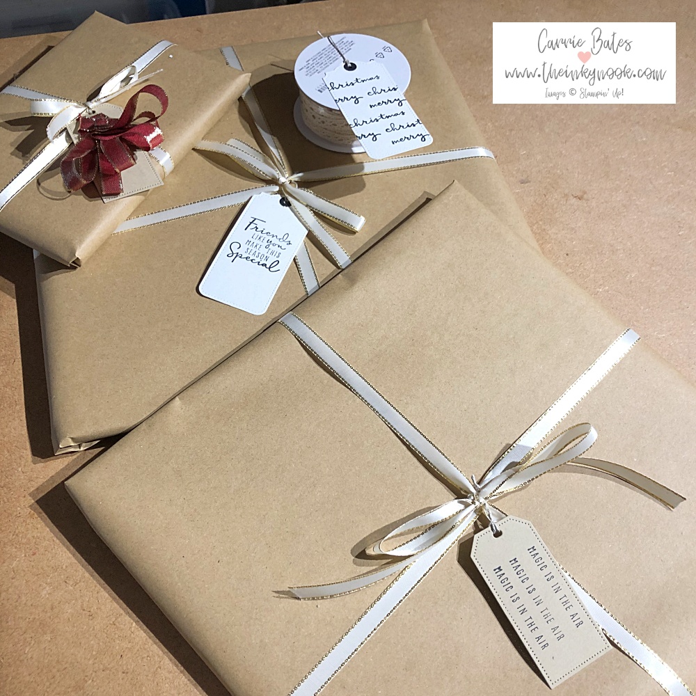 Pile of presents wrapped in kraft paper and tied with cream gold lined ribbon and quick tags