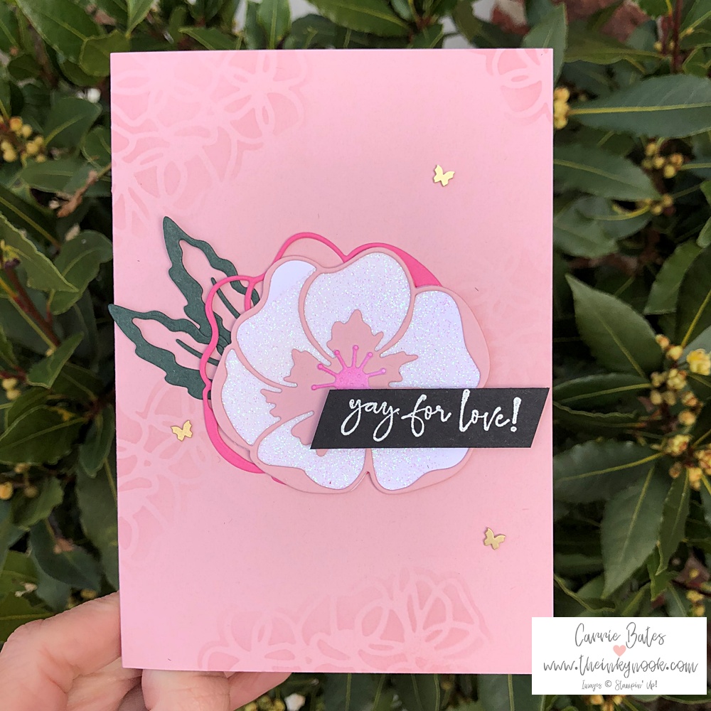 All in pink card celebrating love with detailed floral images and a poppy centrepiece made from diecut images. Everything is pink except for the green leaves and black greeting saying "yay for love". Some gold butterflies adorn the card