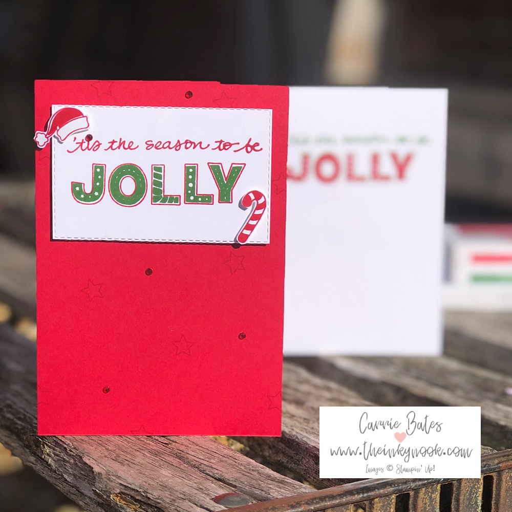 Simple Christmas card idea showing a red card base topped with a white stitched effect rectangle. Stamped with the greeting "tis the season to be jolly" in red and green ink. The top left corner has a santa hat and the bottom right corner has a candy cane.