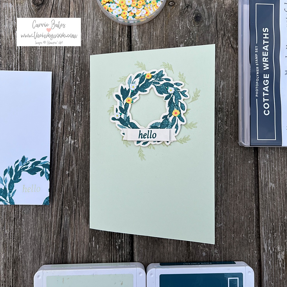 Simple card sketch showing a green wreath topped with a "hello" greeting label on top of a soft green card base stamped with some matching oak leaves