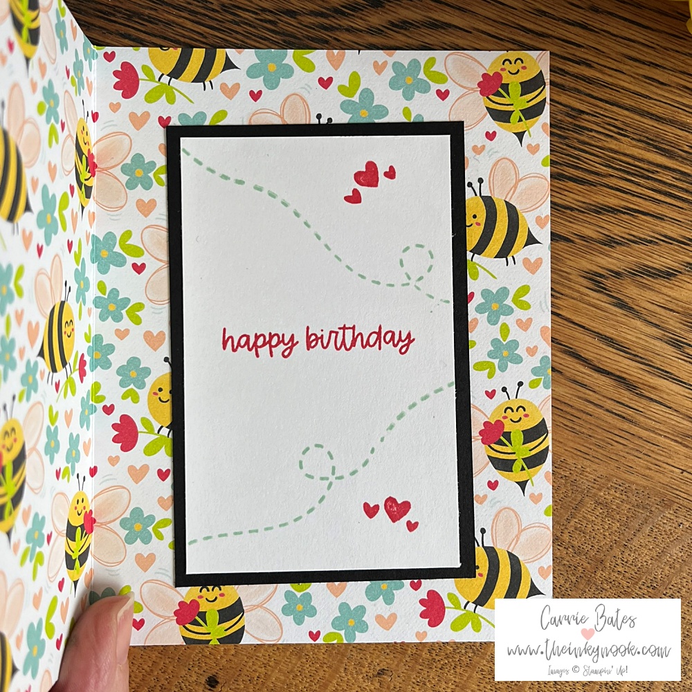 Inside layer of fun fold accordion card showing red happy birthday greeting on a white background stamped with hearts backed up with floral paper scattered with bumblebees