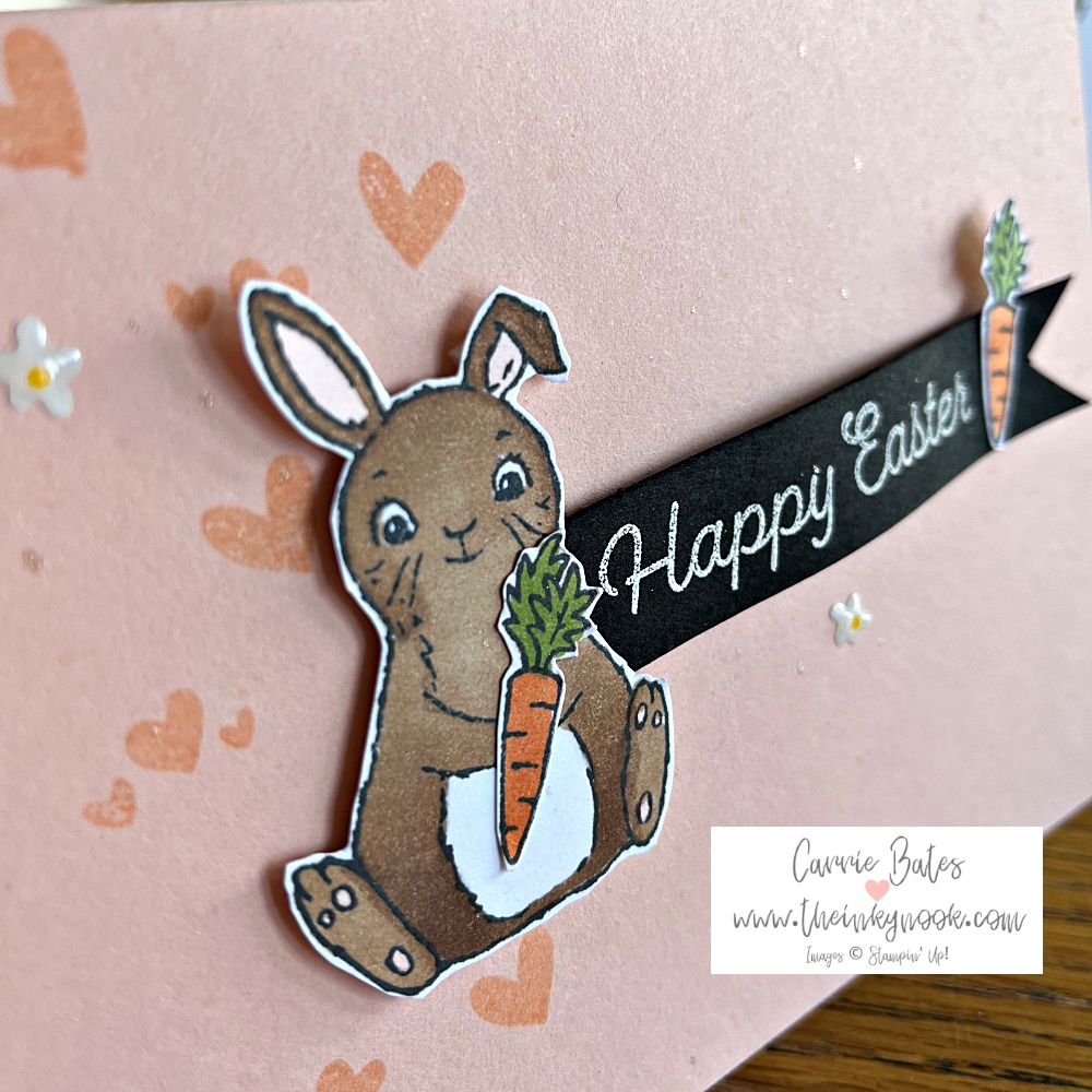 Close up picture of a little brown easter bunny with floppy ears holding a carrot